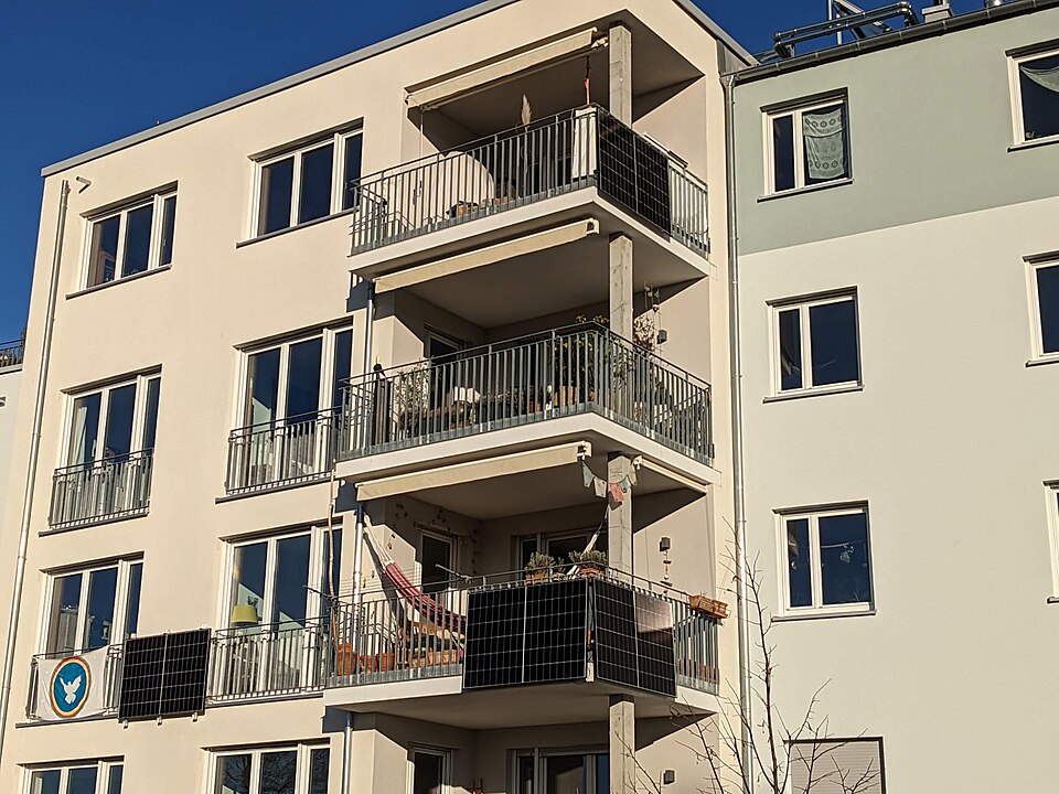 Three solar panels on balconies of a residential building.